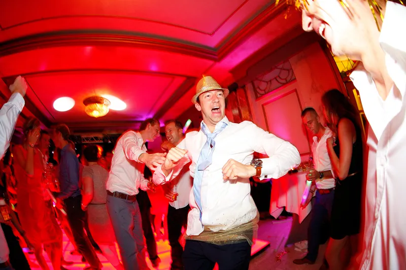 Een gast met hoedje danst in het rode licht