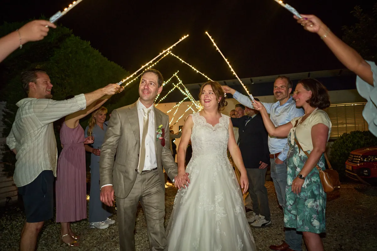 Rutger en Caroline lopen onder een boog van ledlampjes naar buiten