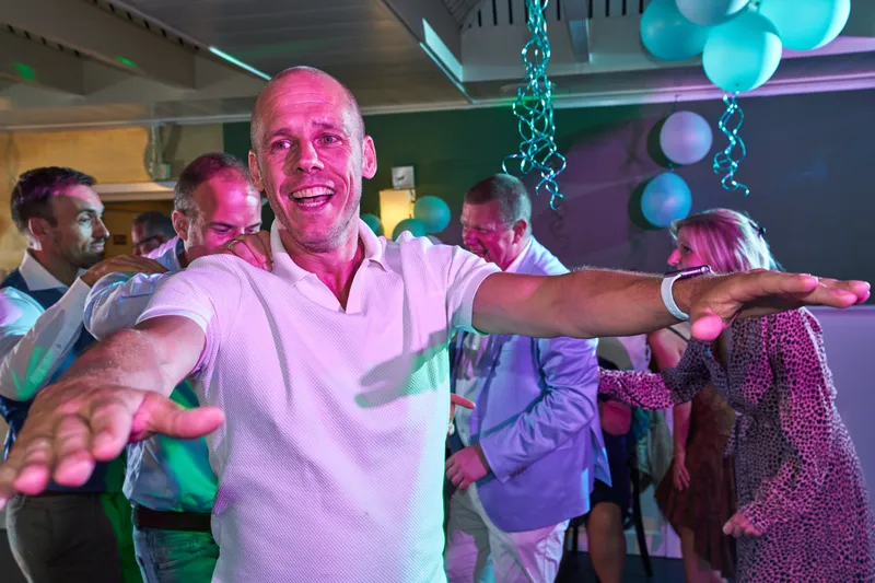 Een gast juicht met gespreide armen op de dansvloer