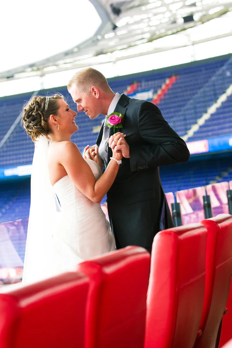 Michelle en Sven dansen tussen de rode stoelen in De Kuip