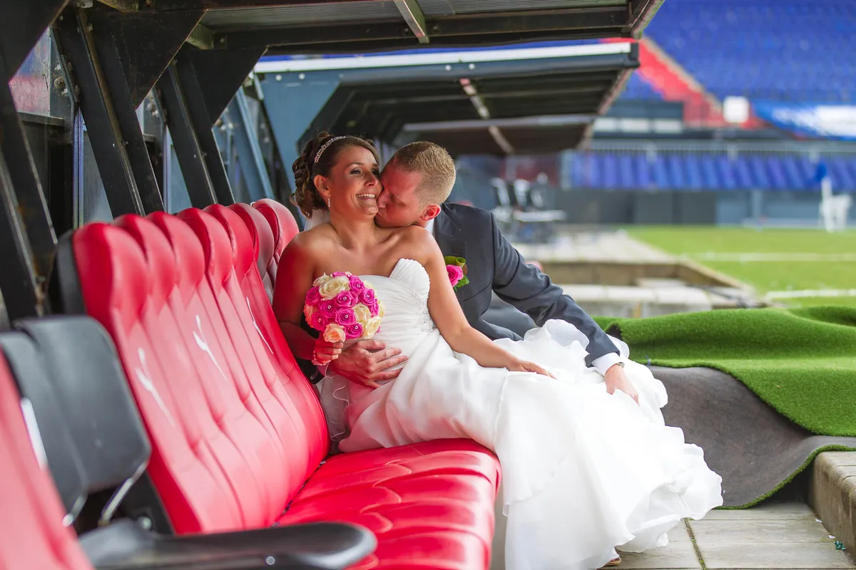 Michelle en Sven in de rode stoelen van de dug-out langs het veld