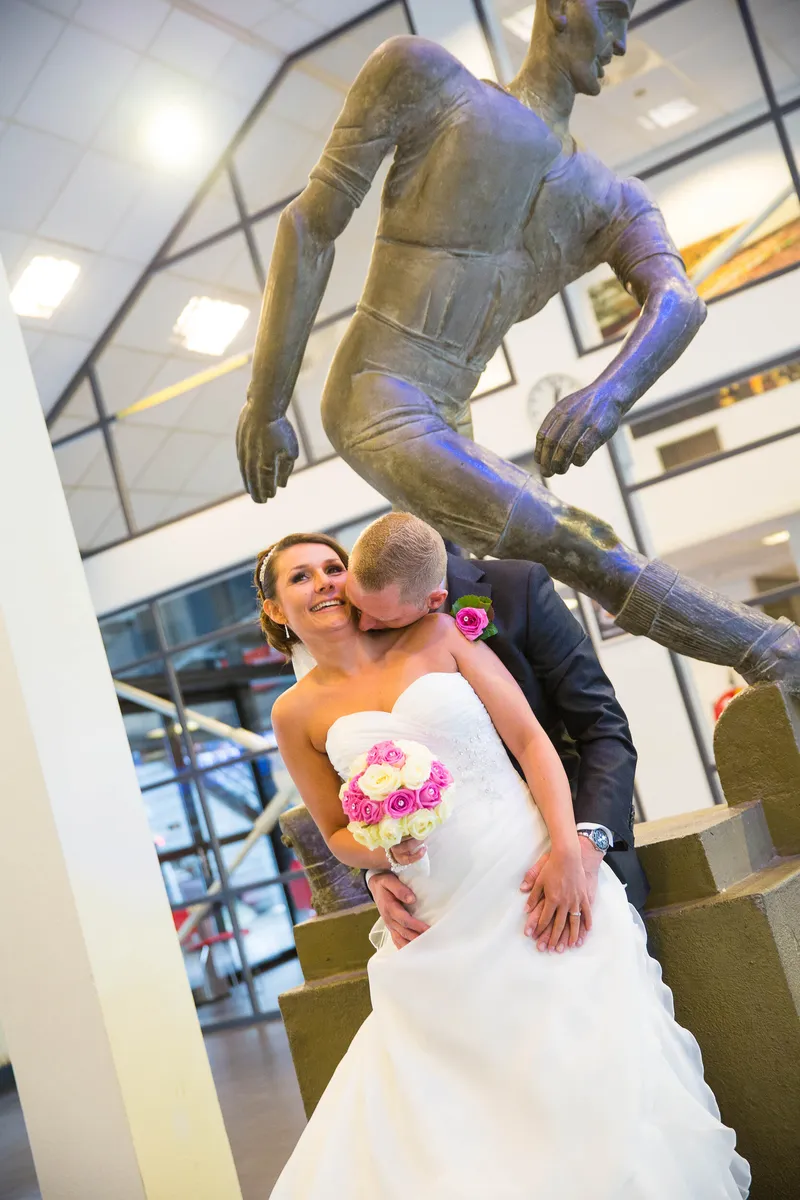 Michelle en Sven kussen bij een bronzen beeld van een voetballer