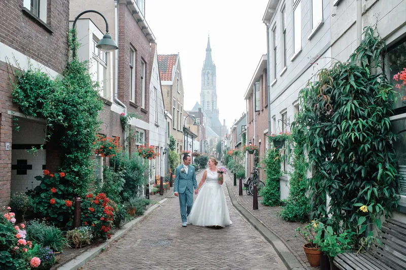 Rick en Milou lopen door een klinkerstraat met een toren aan het eind