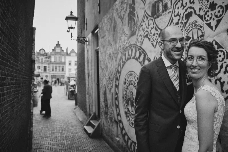 Ilse en Robbert lachen voor een muurschildering in een Delfts steegje