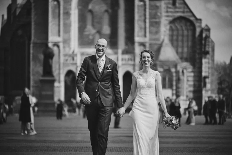 Ilse en Robbert lopen lachend over de Markt, de Nieuwe Kerk erachter