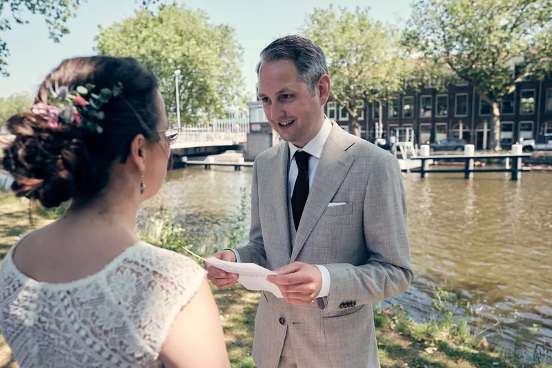 Krijn leest Evelien een brief voor aan het water naast de brug bij de Oostpoort