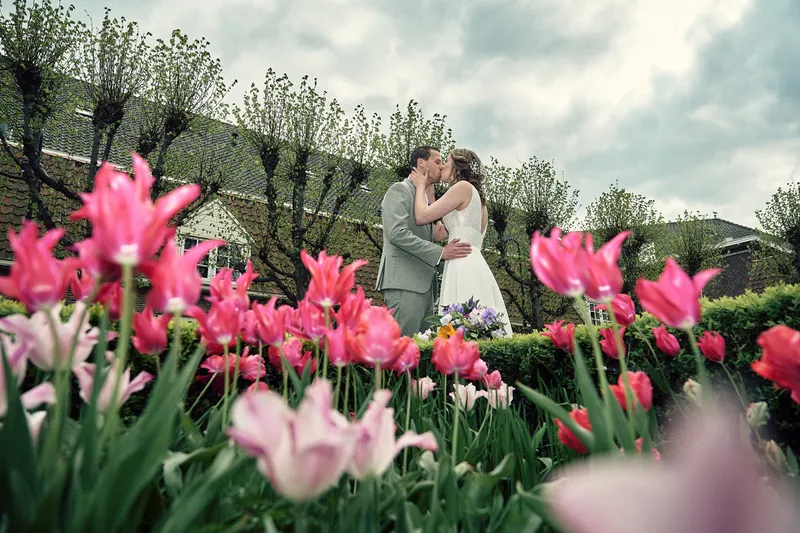 Renske en Tijmen kussen achter roze tulpen en knotwilgen