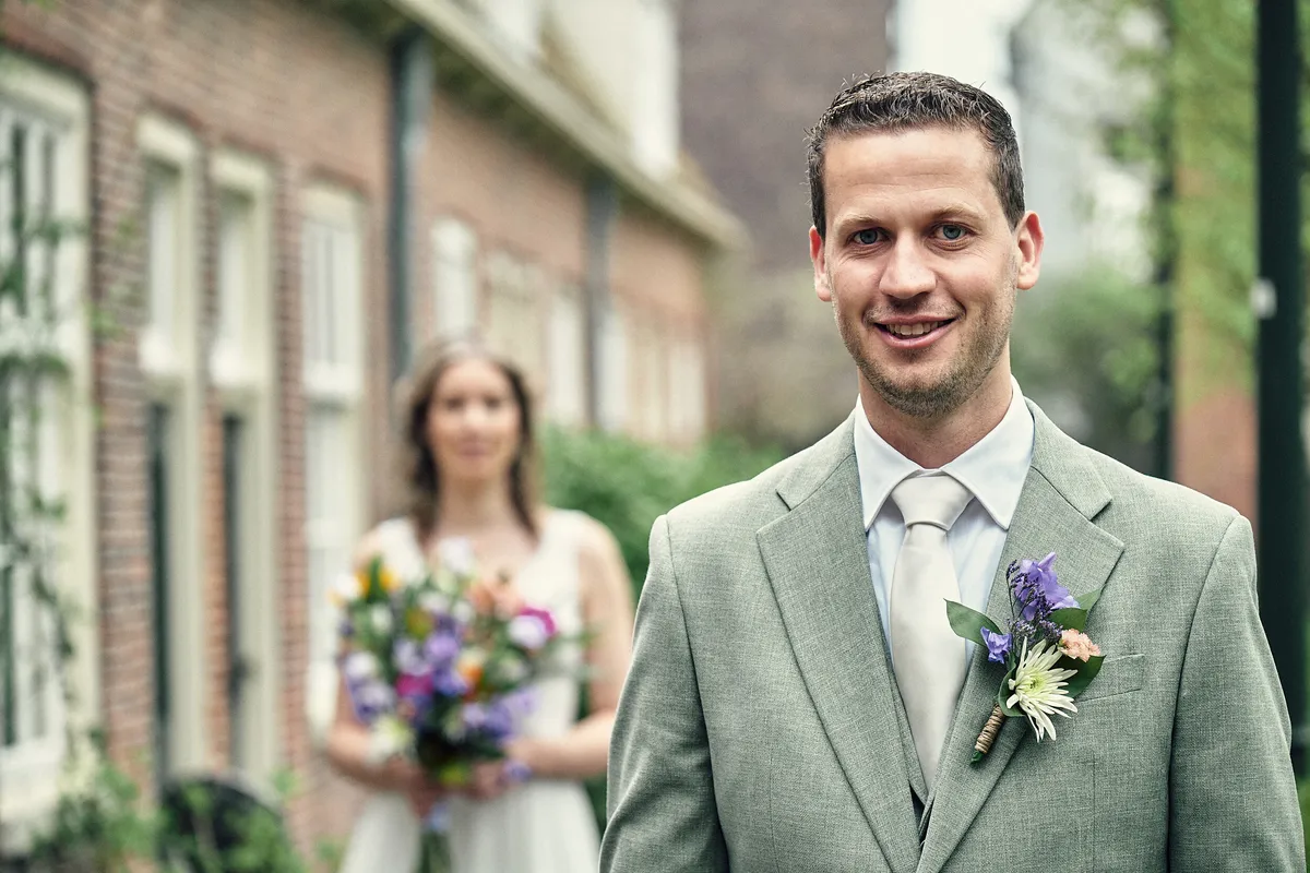 Tijmen lacht in de camera, Renske staat met het boeket achter hem
