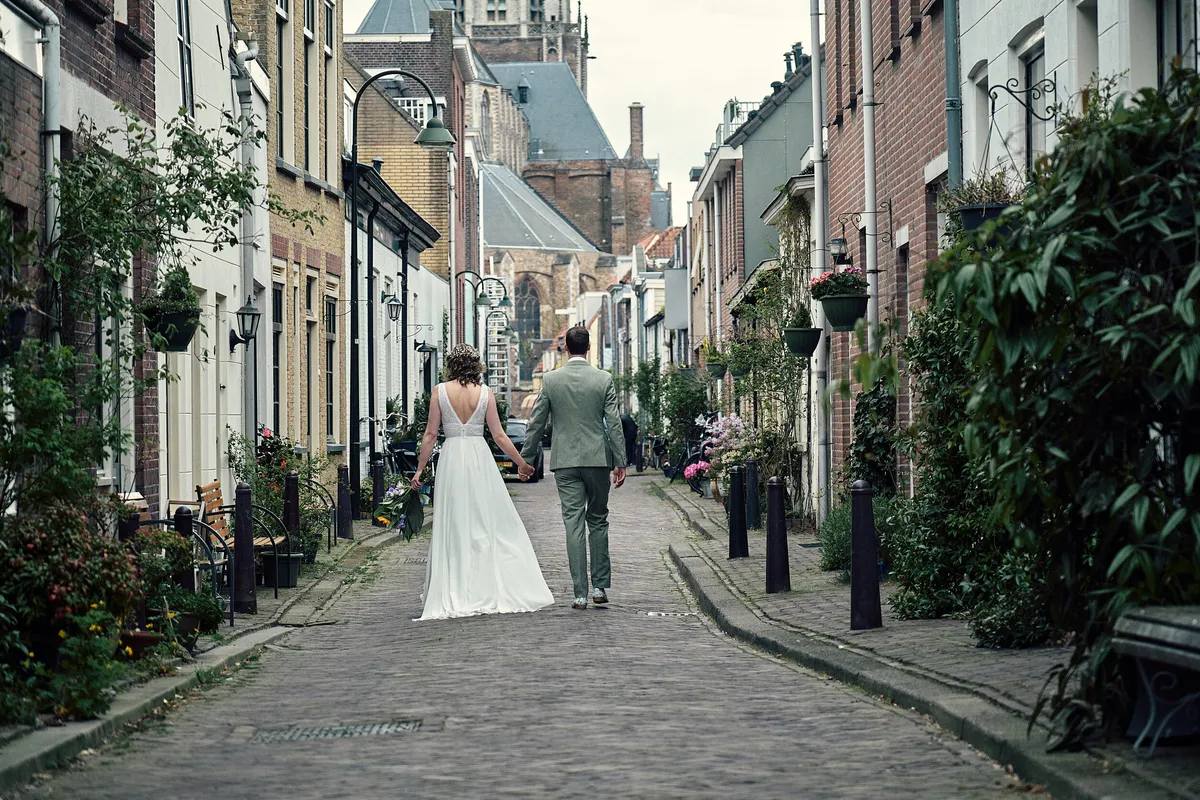 Renske en Tijmen lopen door een smal straatje met een kerktoren aan het eind