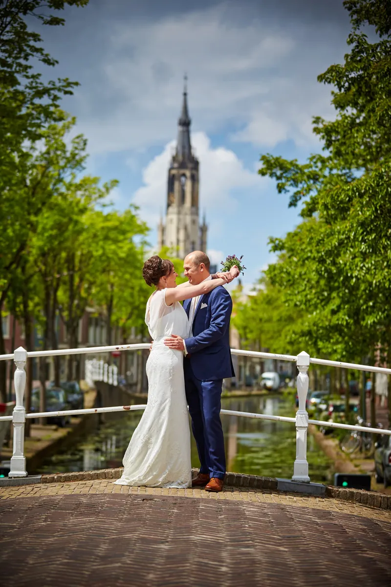 Marina en Erik kussen op een brug over de gracht, met de Nieuwe Kerk erachter