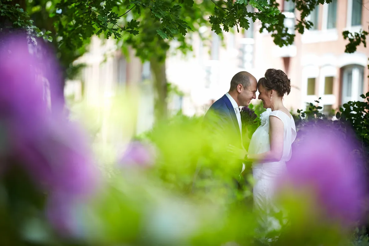 Marina en Erik neus aan neus, met paarse bloemen onscherp op de voorgrond