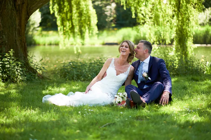 Ingrid en Richard zitten in het gras onder de treurwilgen in de Delftse Hout