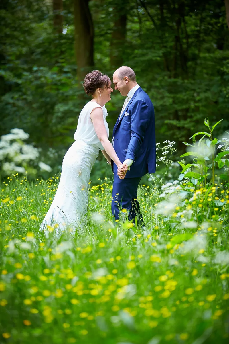 Marina en Erik hand in hand in de weide met gele bloemen