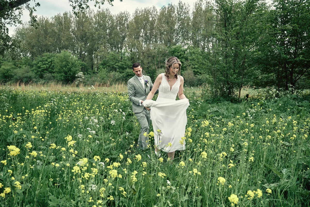 Renske tilt haar jurk op in een veld vol gele bloemen