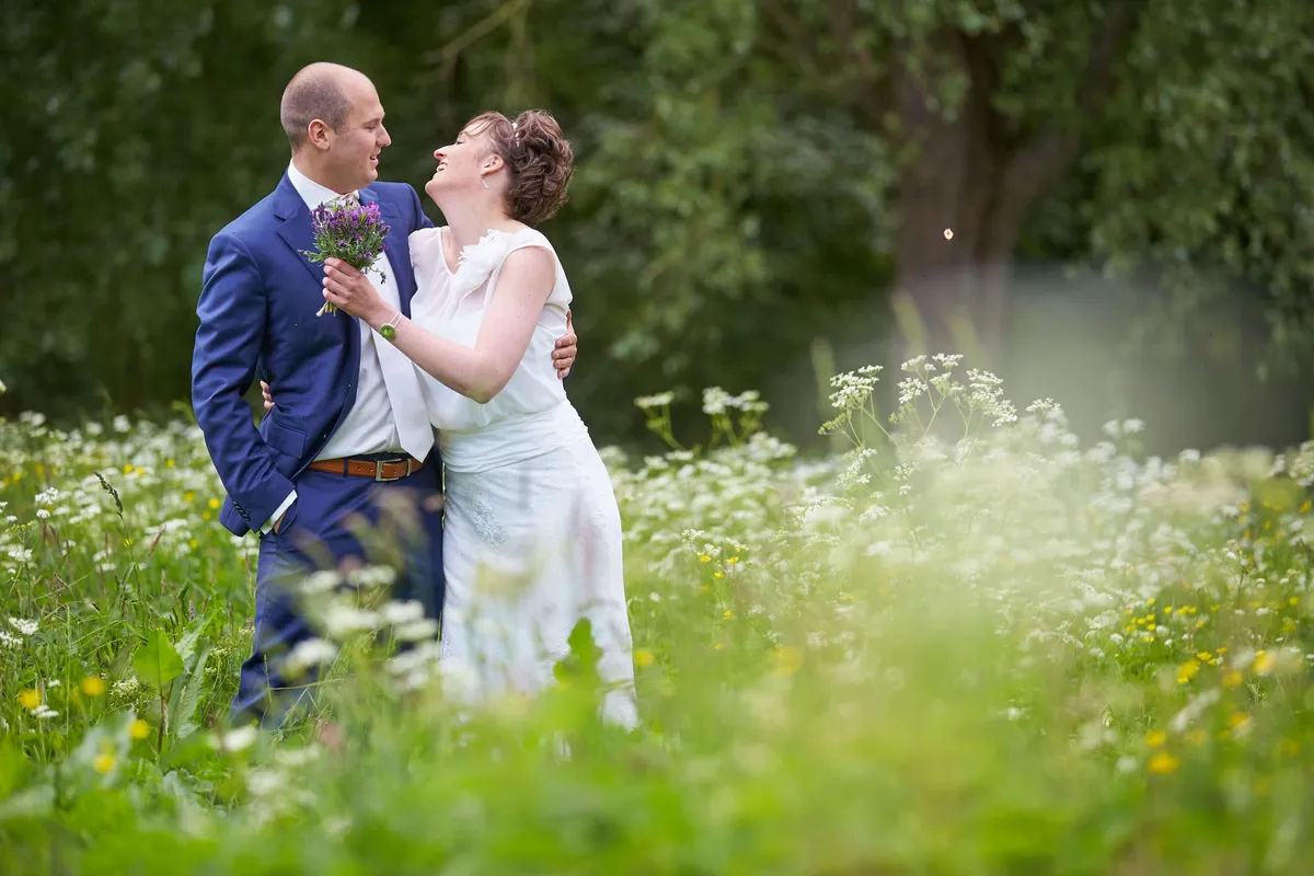 Marina lacht, Erik kijkt naar haar, in de weide met witte bloemen