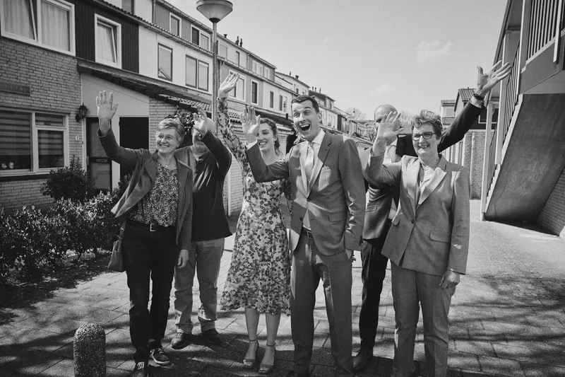 De familie zwaait het bruidspaar uit in de straat
