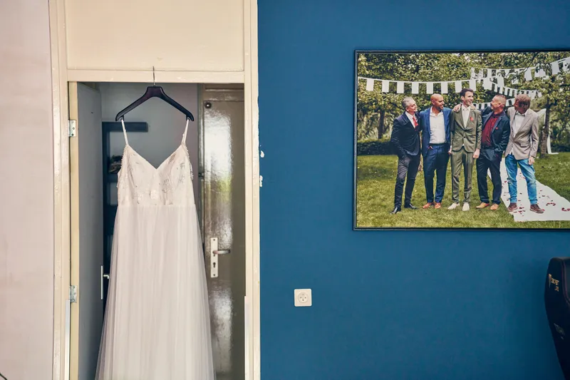 De trouwjurk hangt in de deuropening