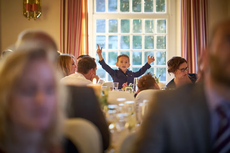 Een gast steekt zijn armen in de lucht aan tafel