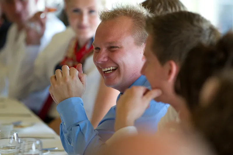 Gasten lachen aan de lange tafel in de serre