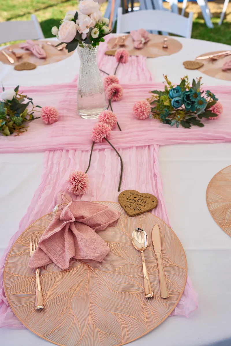 Een gedekte tafel met roze servetten en houten hartjes