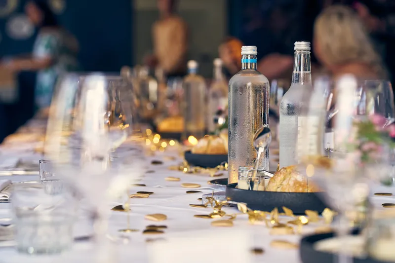 De lange gedekte tafel met glazen en flessen water