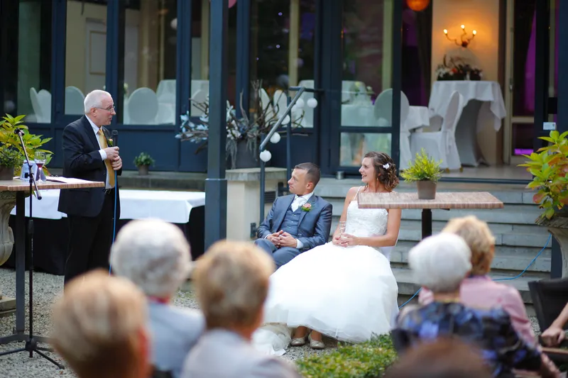 Een speech op het terras, met het bruidspaar op de eerste rij