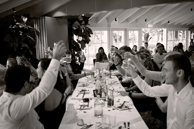 De gasten heffen hun glas aan de lange tafel