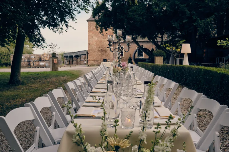 De lange tafel met witte stoelen voor het kasteel