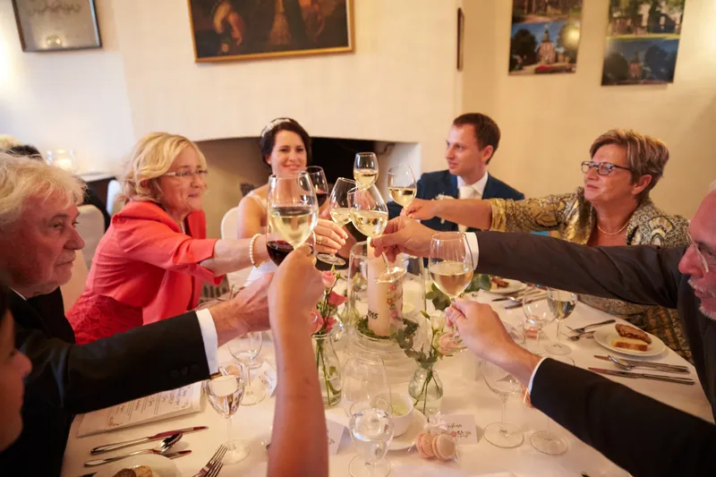 De gasten proosten aan tafel in de grote zaal