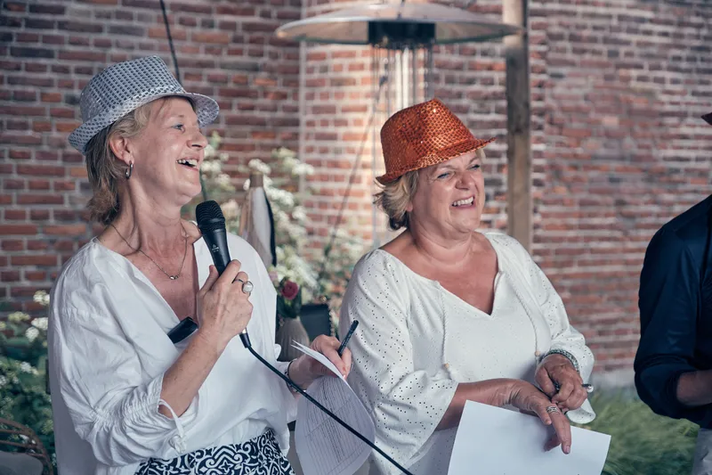 Twee gasten met een hoedje houden samen een speech