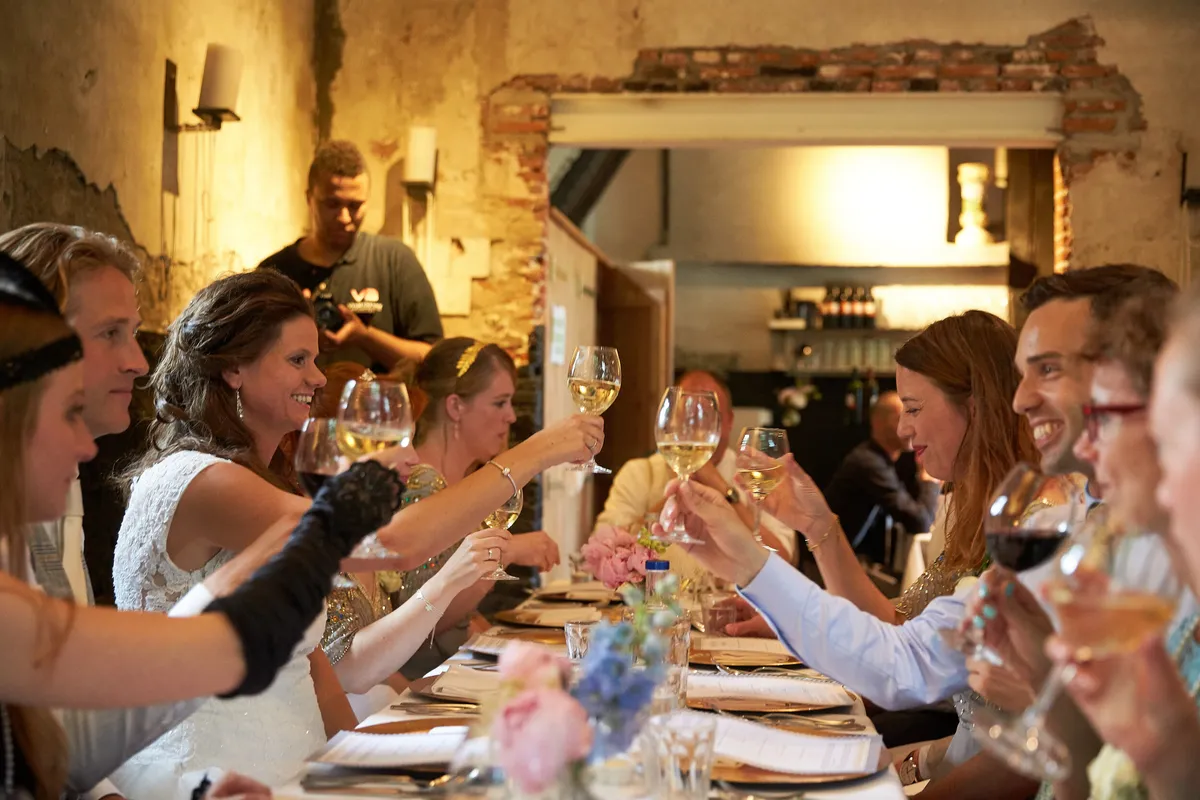 De gasten proosten aan de lange tafel