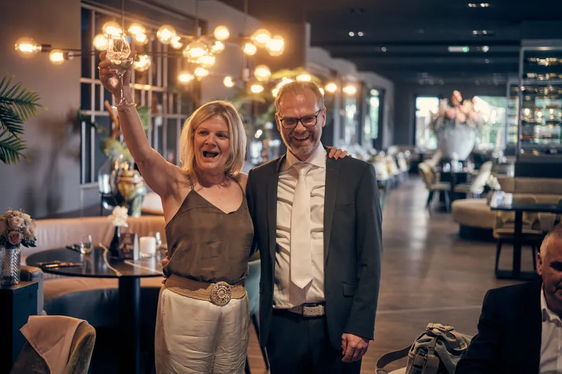 Twee gasten heffen het glas in de zaal met kroonluchters