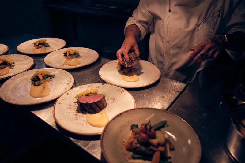 De borden met het hoofdgerecht worden in de keuken opgemaakt
