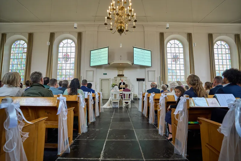 Het middenpad van de Dorpskerk met een koperen kroonluchter