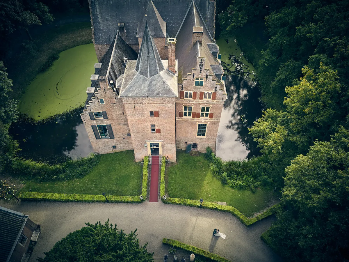 Kasteel Wijenburg van bovenaf, met de gracht, het gras en de bomen eromheen