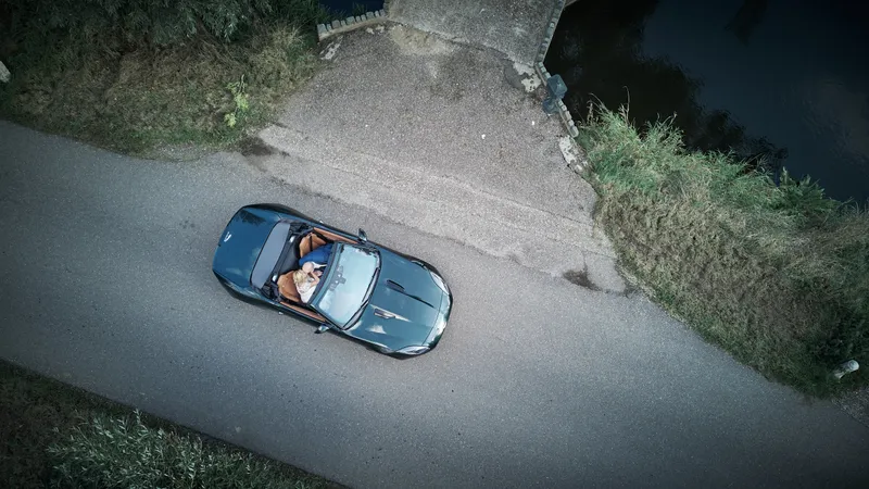 De groene sportwagen op een polderweg, van bovenaf