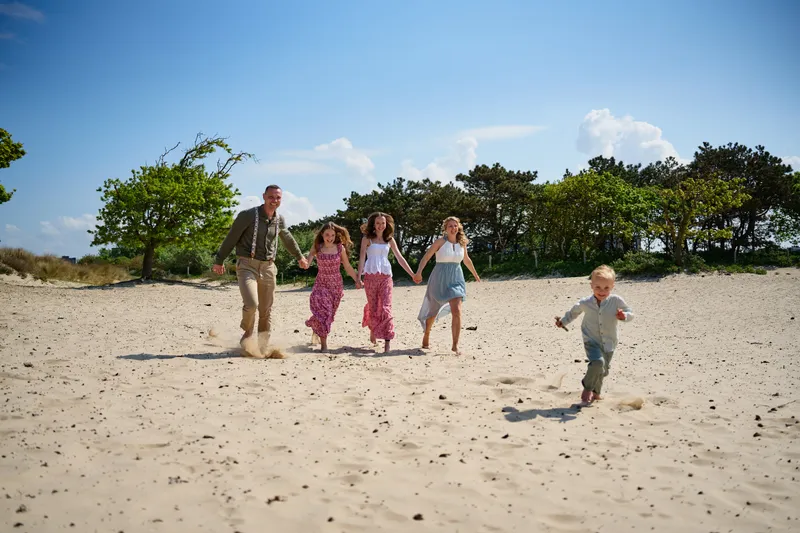 Het gezin rent door het zand in de duinen