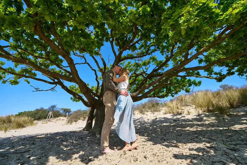 Elise en Erik kussen onder een boom in de duinen