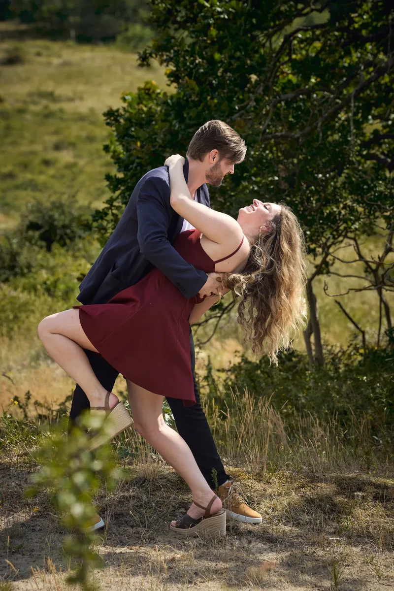 Een koppel in de duinen: hij buigt haar achterover voor een kus