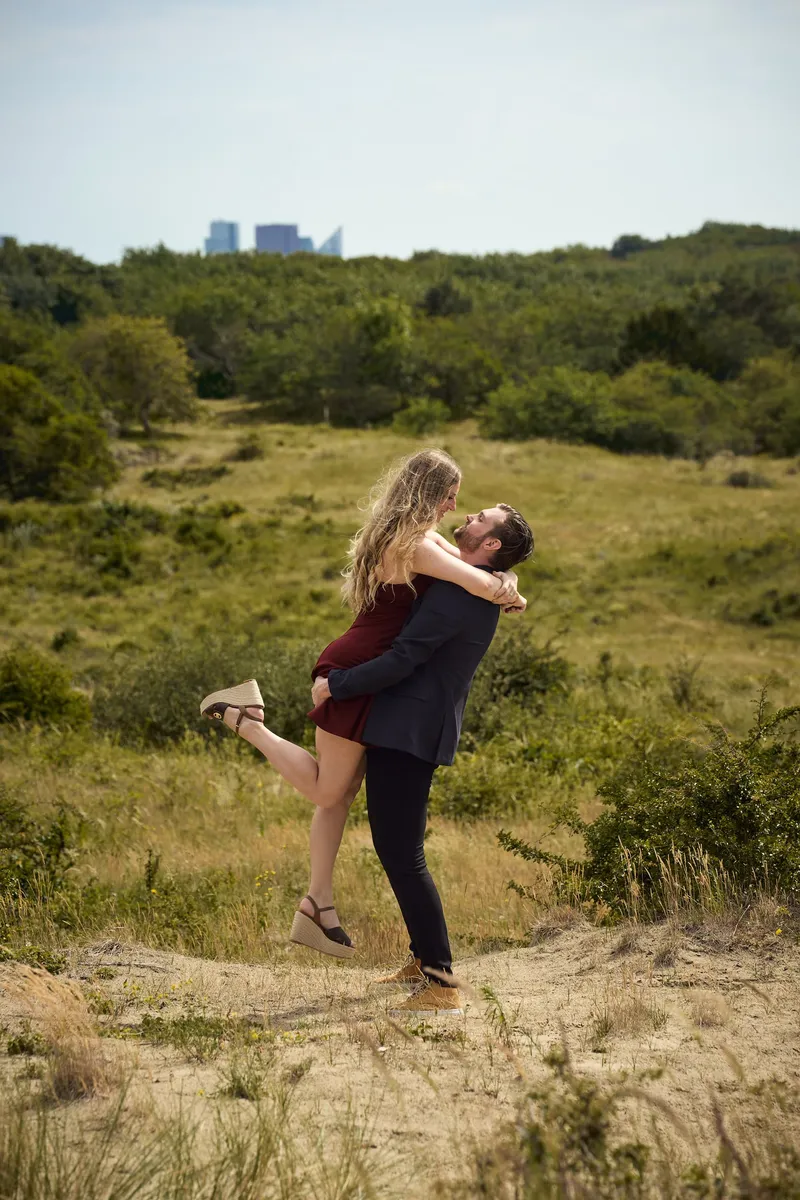 Een koppel in de duinen: hij tilt haar op, zij slaat haar been omhoog