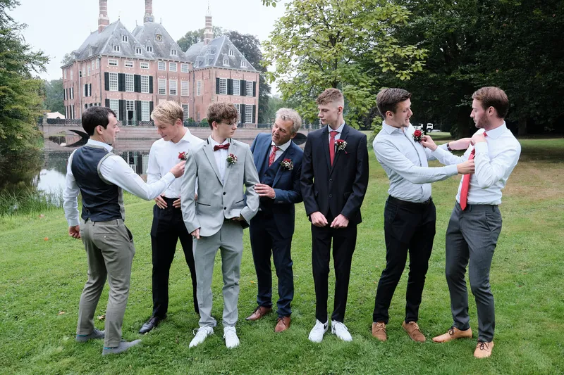 De mannen in pak op het gras bij het kasteel