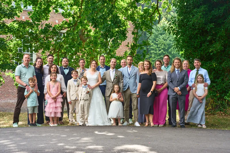 Groepsfoto van familie en vrienden onder de bomen bij het kasteel