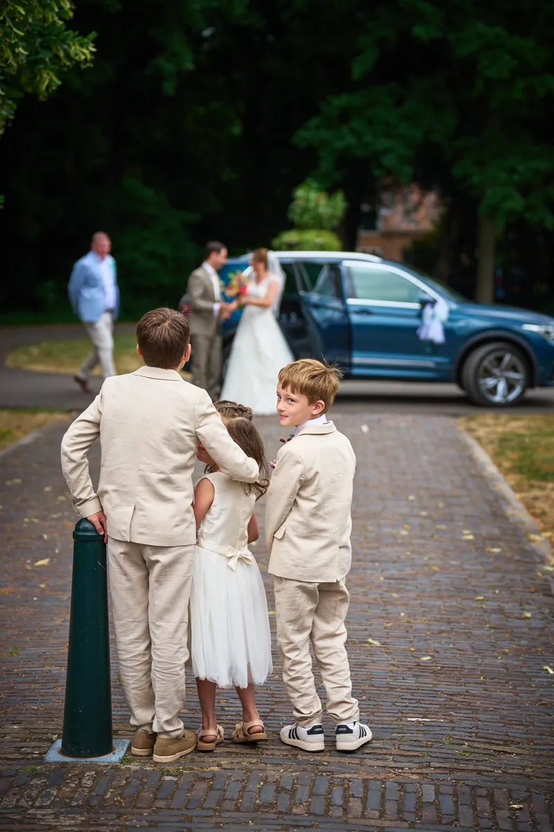 De kinderen wachten op de kinderkopjes, Caroline stapt achter hen uit de auto