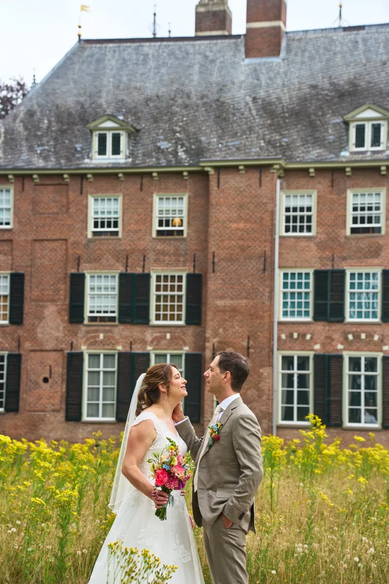 Rutger en Caroline tussen de gele bloemen voor de bakstenen gevel