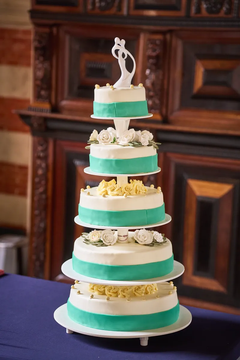 De bruidstaart met mintgroene banden en witte rozen