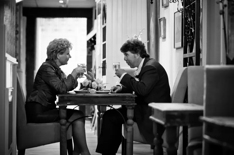 Zwart-wit: Erica en Rob proosten aan het tafeltje bij het raam