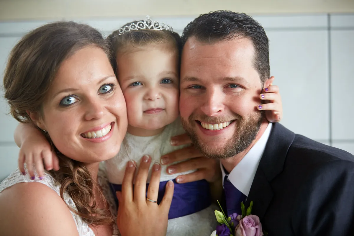 Nadine en Robbert lachen met een meisje met een tiara tussen hen in