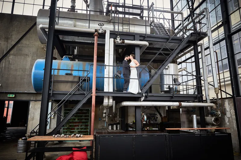 Robbert en Nadine klein tussen de trappen en ketels van de fabriekshal