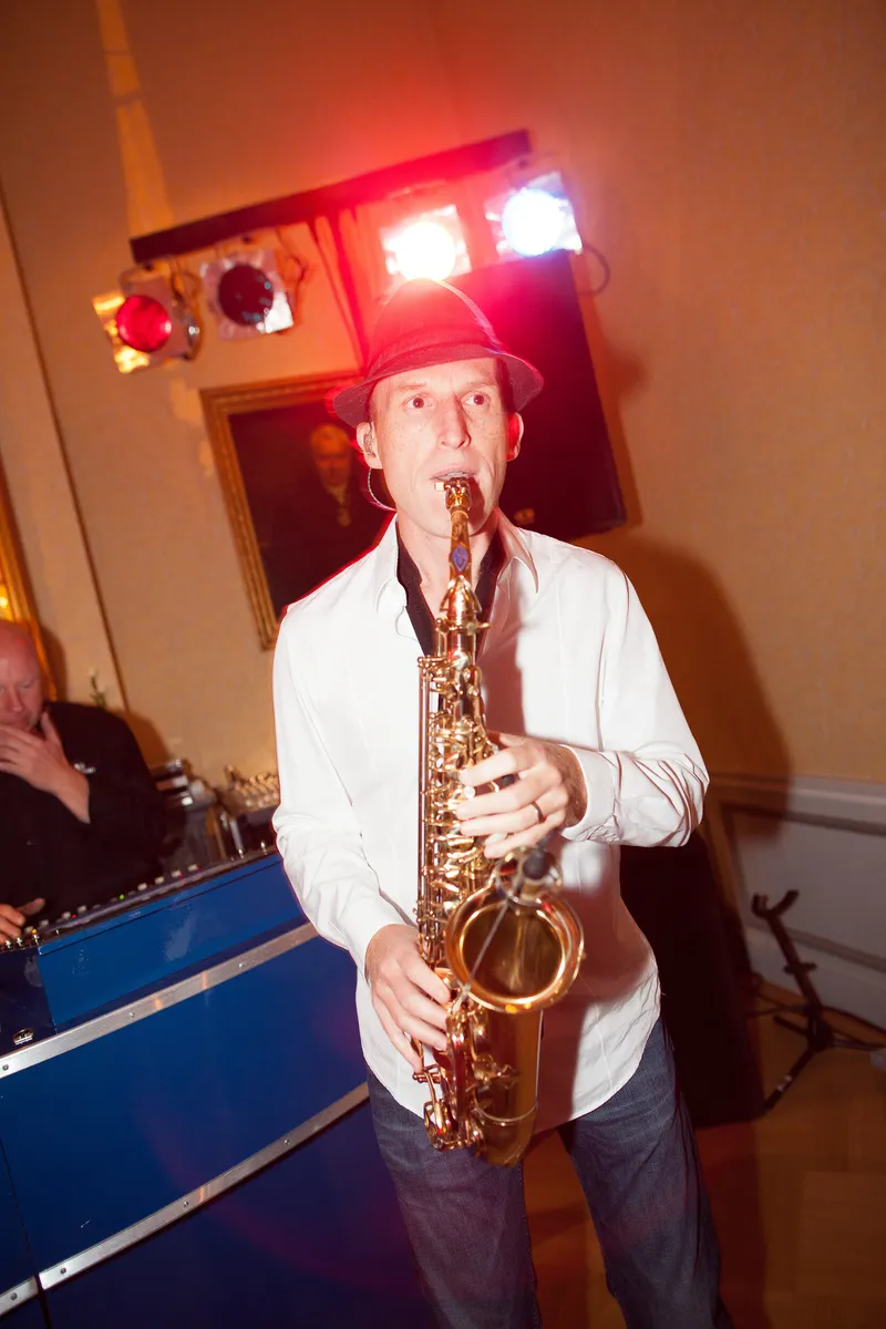 De saxofonist speelt onder de lampen van de dj