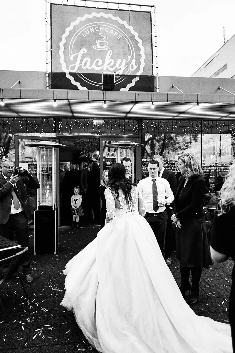 Kimberley loopt onder het bord van Jacky’s naar binnen, met confetti